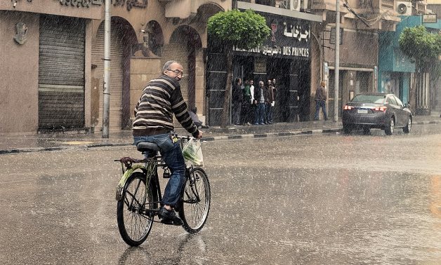 A man riding his bike under the heavy rain in Cairo, Egypt - Wikimedia/Mohamed Hozyen