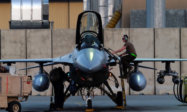 A mechanic climbs into the cockpit of a U.S. Air Force F-16 Fighting Falcon aircraft at Bagram Airfield - REUTERS
