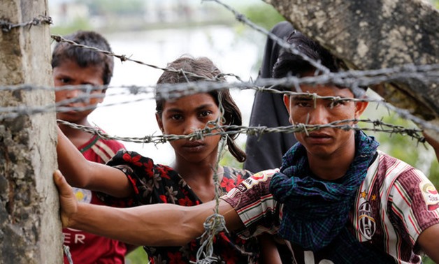 Rohingya refugees looks on through barbed wire as they wait for boat to cross the border through Naf river in Maungdaw, Myanmar - REUTERS