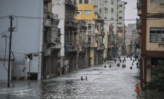 AFP / by Alexandre GROSBOIS | Cubans wade through a flooded street in Havana