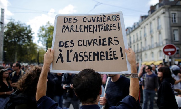 A demonstrator holds a placard which reads "Parliamentary workers, workers at the National Assembly" as he attends a national strike and protest against the government's labor reforms in Nantes - REUTERS