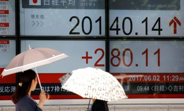FILE PHOTO - Women holding parasols, look at an electronic board showing Japan's Nikkei average outside a brokerage in Tokyo, Japan June 2, 2017. REUTERS/Toru Hanai