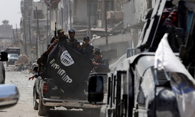 Iraqi police hold a captured Islamic State flag in Mosul (Reuters)