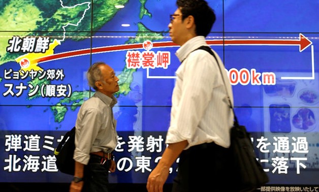 Passersby in Tokyo walk in front of a TV screen reporting news about North Korea's missile launch - REUTERS