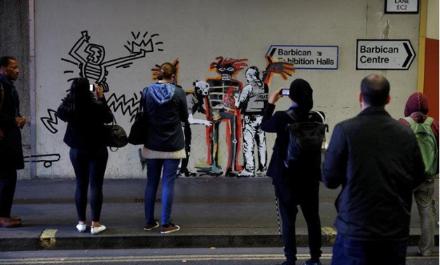 People look as others photograph a mural painted by the artist Banksy near the Barbican Centre in London, Britain, September 18, 2017. REUTERS/Peter Nicholls
