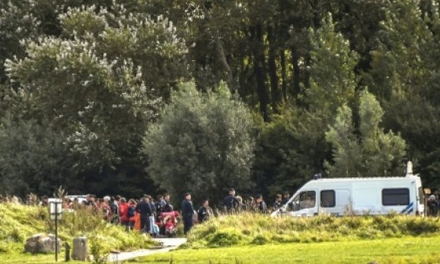 Police monitor migrants in Grande-Synthe, northern France, during the evacuation on September 19, 2017, of a makeshift migrant camp in the Puythouck woods where around 350 Iraqi Kurds where living