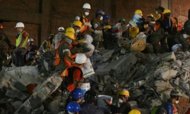 © AFP / by Marc BURLEIGH | Soldiers and volunteers remove rubble from a collapsed building in Colonia Condesa, an area of Mexico City