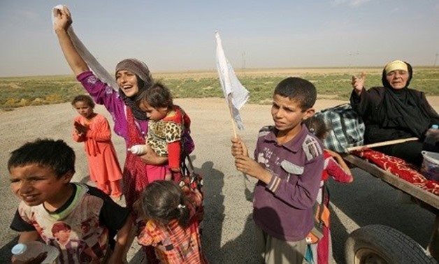 Members of an Iraqi family, displaced from the outskirts of Islamic State group stronghold Hawija, raise white flags while travelling on the road outside the town on October 3, 2017. AFP / AHMAD AL-RUBAYE