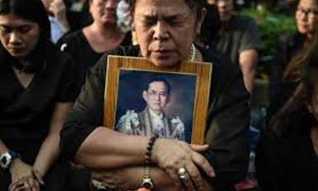 A mourner clutching a picture of Thai King Bhumibol Adulyadej after the hearse carrying the body of the late monarch passed the Grand Palace in Bangkok last year - AFP