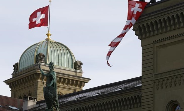 Workers hang up a Swiss flag on the Swiss parliament building in Bern, Switzerland, November 24, 2015. REUTERS/Ruben Sprich