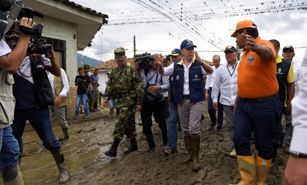 Colombia's President Juan Manuel Santos walks down a street after floods and landslides, caused by heavy rains where a river overflowed, pushed sediments and rocks into houses and roads, in Corinto - REUTERS