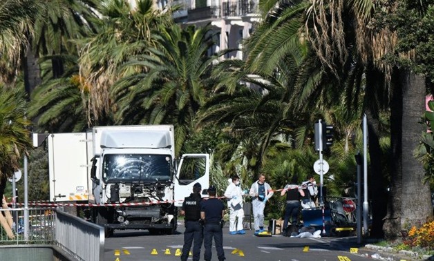 Forensic officers and police look for evidences near a truck on the Promenade des Anglais seafront in the French Riviera town of Nice on July 15, 2016, after it drove into a crowd watching a fireworks display - AFP