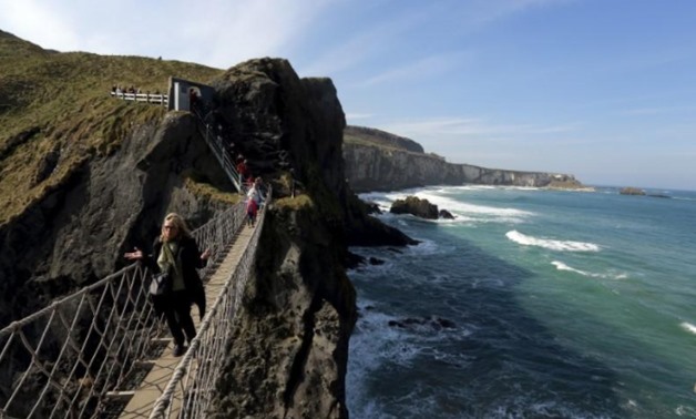 Tourists make their way across Carrick-a-Rede Rope Bridge on the Causeway coast, north of Belfast April 8, 2015. The bridge is suspended 30 metres above sea level and was built 350 years ago by salmon fishermen, according to conservation organisation Nati