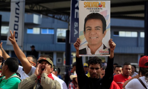 A supporter of Salvador Nasralla, presidential candidate for the Opposition Alliance Against the Dictatorship, holds up a poster of Nasralla while waiting for official presidential election results outside at the Supreme Electoral Tribunal in Tegucigalpa,