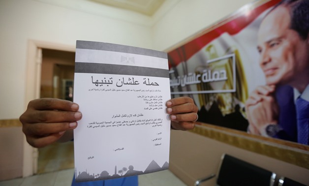 A man hold a paper of "To build it" campaign to support President Sisi for another term-  Egypt Today / Hassan Mohamed 