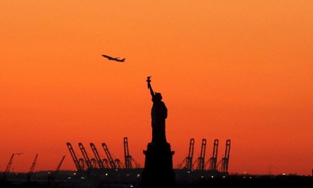 A plane is seen during take off in New Jersey behind the Statue of Liberty in New York's Harbor as seen from the Brooklyn borough of New York February 20, 2016. REUTERS/Brendan McDermid/File Photo