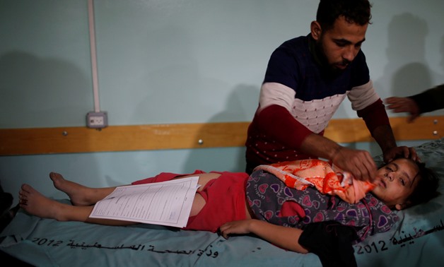 A man tends to a wounded Palestinian girl following Israeli airstrikes on nearby militant targets, at a hospital in the northern Gaza Strip December 8, 2017. REUTERS/Mohammed Salem