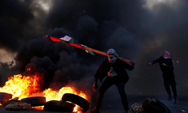 A demonstrator holds a Palestinian flag during clashes with Israeli troops at a protest against U.S. President Donald Trump's decision to recognize Jerusalem as Israel's capital, near the Jewish settlement of Beit El, near the West Bank city of Ramallah D