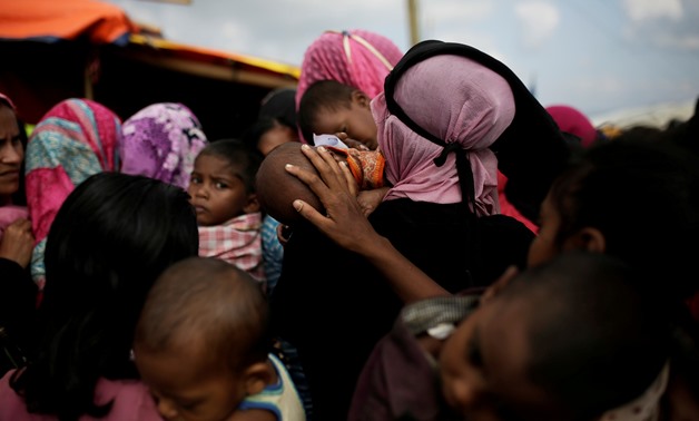 A woman calms a baby as Rohingya refugees line up for a food supply distribution at the Kutupalong refugee camp near Cox's Bazar, Bangladesh December 12, 2017. REUTERS/Alkis Konstantinidis TPX IMAGES OF THE DAY