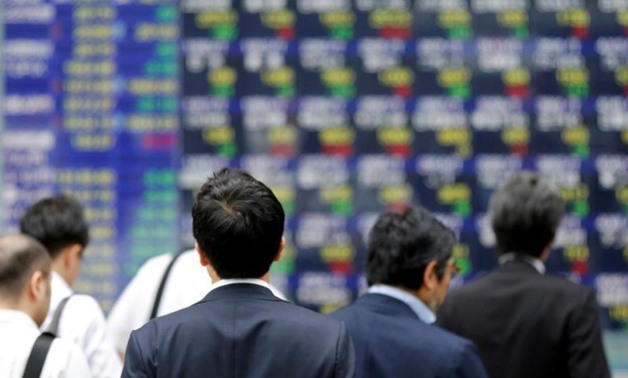 People walk past an electronic stock quotation board outside a brokerage in Tokyo, Japan, September 22, 2017 - REUTERS/Toru Hanai/File Photo