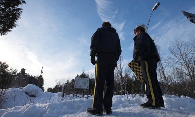 Royal Canadian Mounted Police (RCMP) officers stand on a hill looking over the U.S.-Canada border into Hemmingford, Quebec, Canada February 14, 2017. REUTERS/Christinne Muschi