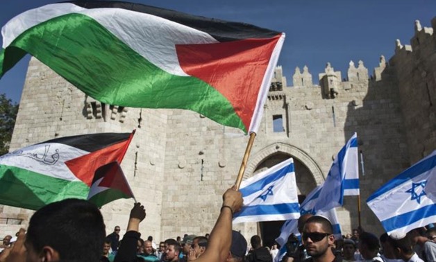 Palestinian protesters wave Palestinian flags as Israelis carrying Israeli flags, while protesting outside the Damascus Gate in Jerusalem's Old City – Reuters