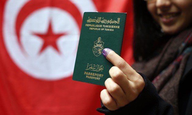 A Tunisian woman shows her passport and her inked finger in the Tunisian consulate in Paris (AFP)