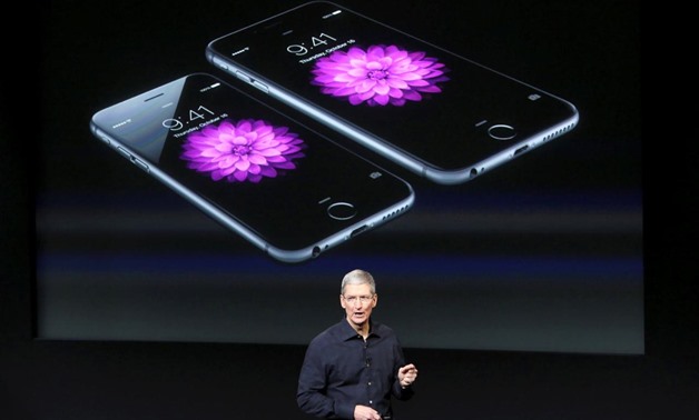 FILE PHOTO: Apple CEO Tim Cook stands in front of a screen displaying the IPhone 6 during a presentation at Apple headquarters in Cupertino, California October 16, 2014. REUTERS/Robert Galbraith