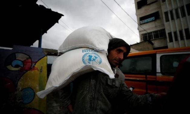 FILE PHOTO: A Palestinian man carries sacks of flour outside a United Nations food distribution center in Al-Shati refugee camp in Gaza City December 6, 2017. REUTERS/Mohammed Salem