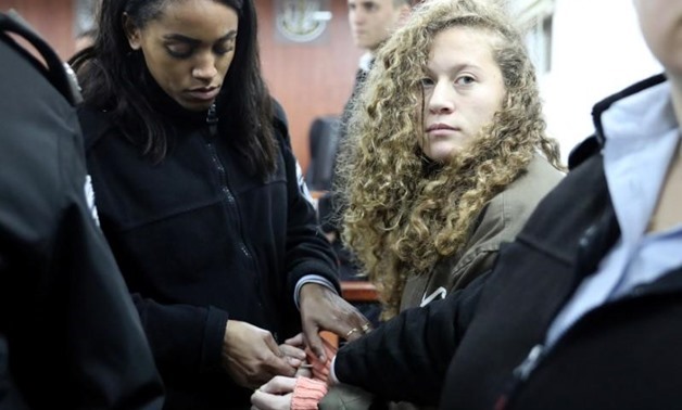 Palestinian teen Ahed Tamimi (R) enters a military courtroom escorted by Israeli Prison Service personnel at Ofer Prison, near the West Bank city of Ramallah, January 1, 2018. REUTERS/Ammar Awad