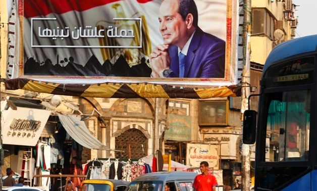 People walk near a poster of Egyptian President Abdel Fattah al-Sisi of the campaign titled, "Alashan Tabneeha" (So You Can Build It), Egypt, October 17, 2017 – Reuters