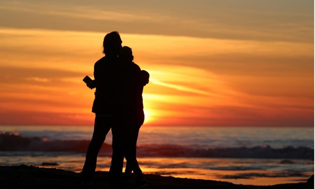 A couple embraces as they watch the sun set in Solana Beach, California, U.S., January 4, 2018. REUTERS/Mike Blake