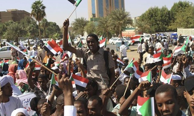 Government supporters gather in front of military headquarters in Khartoum and wave national flags after learning that JEM leader Khalil Ibrahim had been killed - Reuters