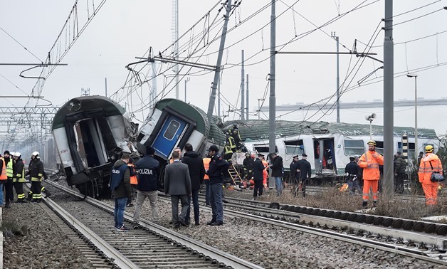 Rescue workers and police officers stand near derailed trains in Pioltello, on the outskirts of Milan, Italy, January 25, 2018. REUTERS/Stringer