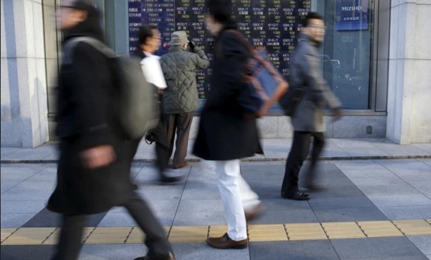 A man (3rd L) looks at an electronic stock quotation board as passers-by walk past, outside a brokerage in Tokyo, Japan January 20, 2016. REUTERS/Toru Hanai