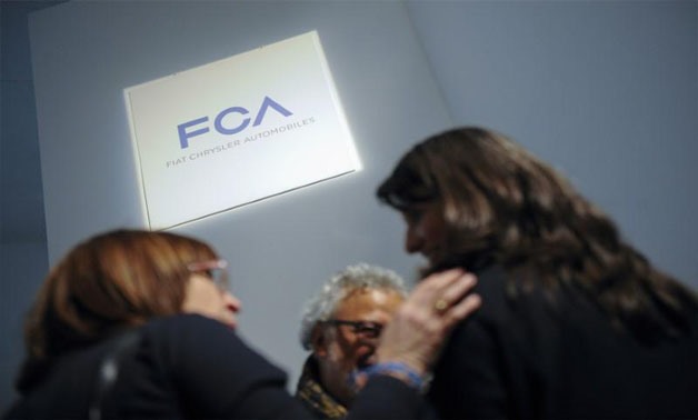 People talk as they stand next to a logo of Fiat Chrysler Automobiles (FCA) in Turin, Italy on March 31, 2014 -
 REUTERS/Giorgio Perottino/File Photo