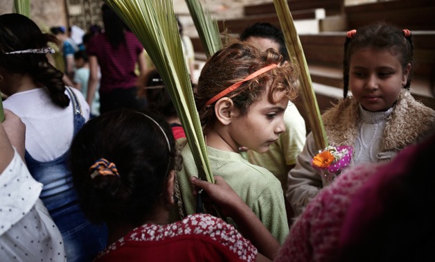 Christian children hold palm fonds during the Palm Sunday mass inside a church in Cairo - Reuters