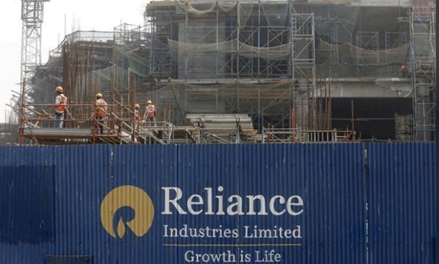 FILE PHOTO: Labourers work behind an advertisement of Reliance Industries Limited at a construction site in Mumbai, India, March 2, 2016. REUTERS/Shailesh Andrade/File Photo
