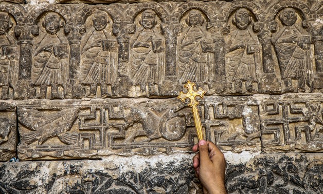 A priest points with his cross at carving inside Jebel el-Teir Monastery in Minya Upper Egypt in October 2017 - Maher Eskandar