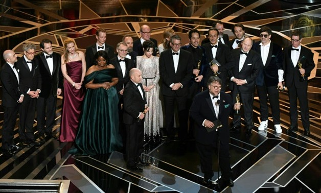 Mexican director Guillermo del Toro (C) delivers a speech surrounded by his cast and crew from "The Shape of Water" as he accepted the Oscar for best picture
