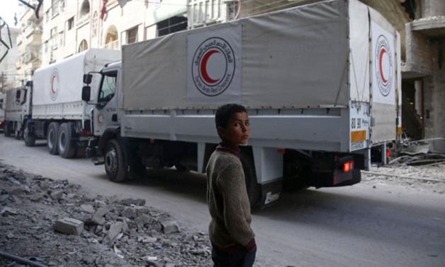 A boy stands as an aid convoy of Syrian Arab Red Crescent drives through the besieged town of Douma, Eastern Ghouta, Damascus, Syria March 5, 2018. REUTERS/Bassam Khabieh