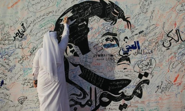 A man writes on a painting depicting Qatar’s Emir Sheikh Tamim Bin Hamad Al-Thani in Doha, Qatar, July 2, 2017. REUTERS/Naseem Zeitoon (REUTERS)