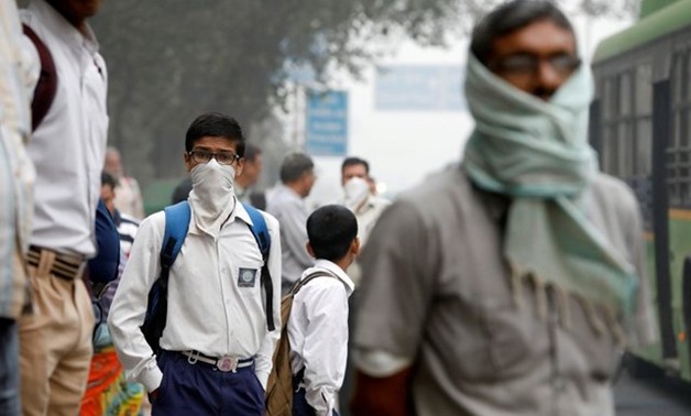 FILE PHOTO: A schoolboy covers his face with a handkerchief as he waits for a passenger bus on a smoggy morning in New Delhi - Reuters