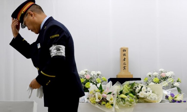 Train employees pay their respects at the site where passengers were overcome by sarin gas - AFP 
