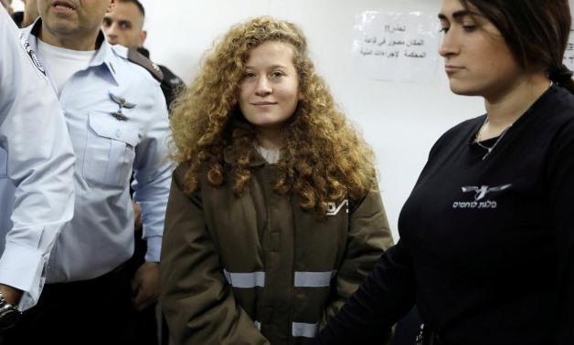 Palestinian teen Ahed Tamimi enters a military courtroom escorted by Israeli security personnel at Ofer Prison, near the West Bank city of Ramallah, January 15, 2018 - REUTERS/Ammar Awad/File Photo