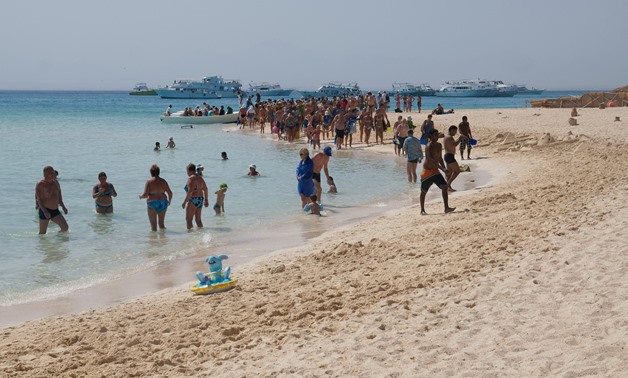 Tourists walking on the beach of Paradise Island of Hurghada. Tourist boats are in the background – CC via Wikimedia Commons/kallerna