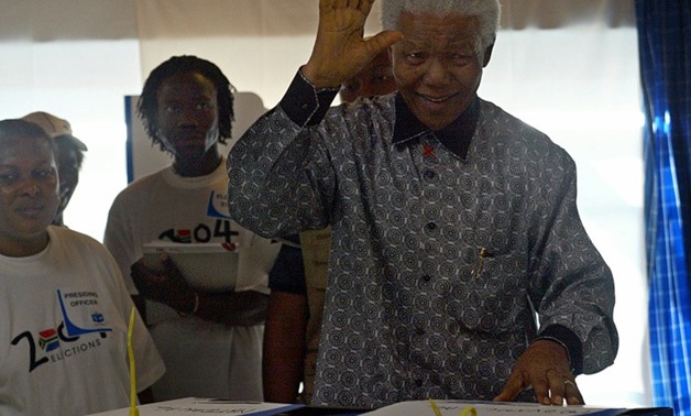 Former South African President Nelson Mandela gestures after casting his vote for his country's third democratic general election in 2004