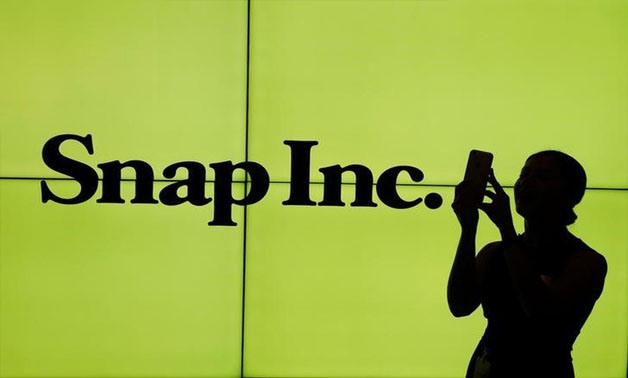 A woman stands in front of the logo of Snap Inc. on the floor of the New York Stock Exchange (NYSE) while waiting for Snap Inc. to post their IPO, in New York City, NY, U.S. March 2, 2017. REUTERS/Lucas Jackson