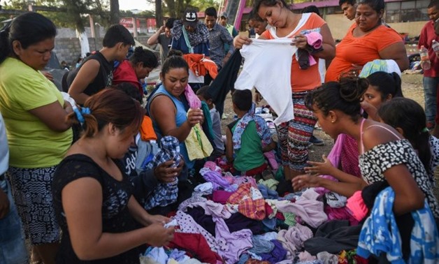 Central American migrants taking part in the "Migrant Via Crucis" caravan towards the United States chooses clothes from a donated pile as they camp at a sport complex in Matias Romero, Oaxaca
