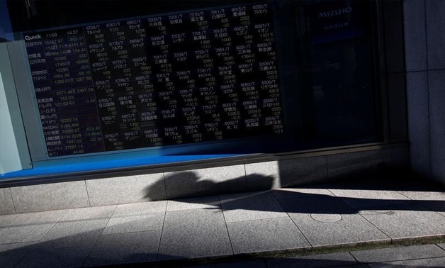 A pedestrian casts a shadow in front of an electronic stock quotation board outside a brokerage in Tokyo, Japan, November 9, 2016. REUTERS/Issei Kato/File photo